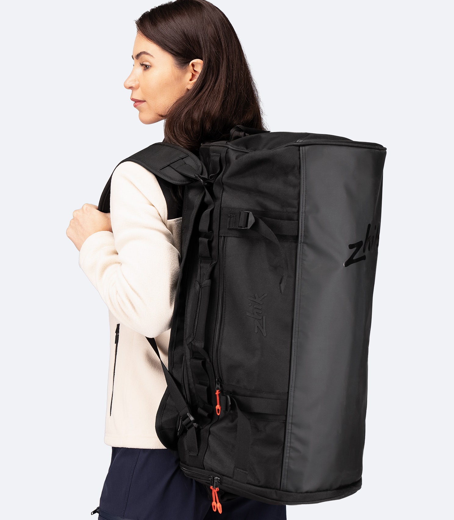 Model wearing the Zhik 55L Duffel Bag in black as a backpack, showing padded straps and ergonomic fit for carrying heavy gear