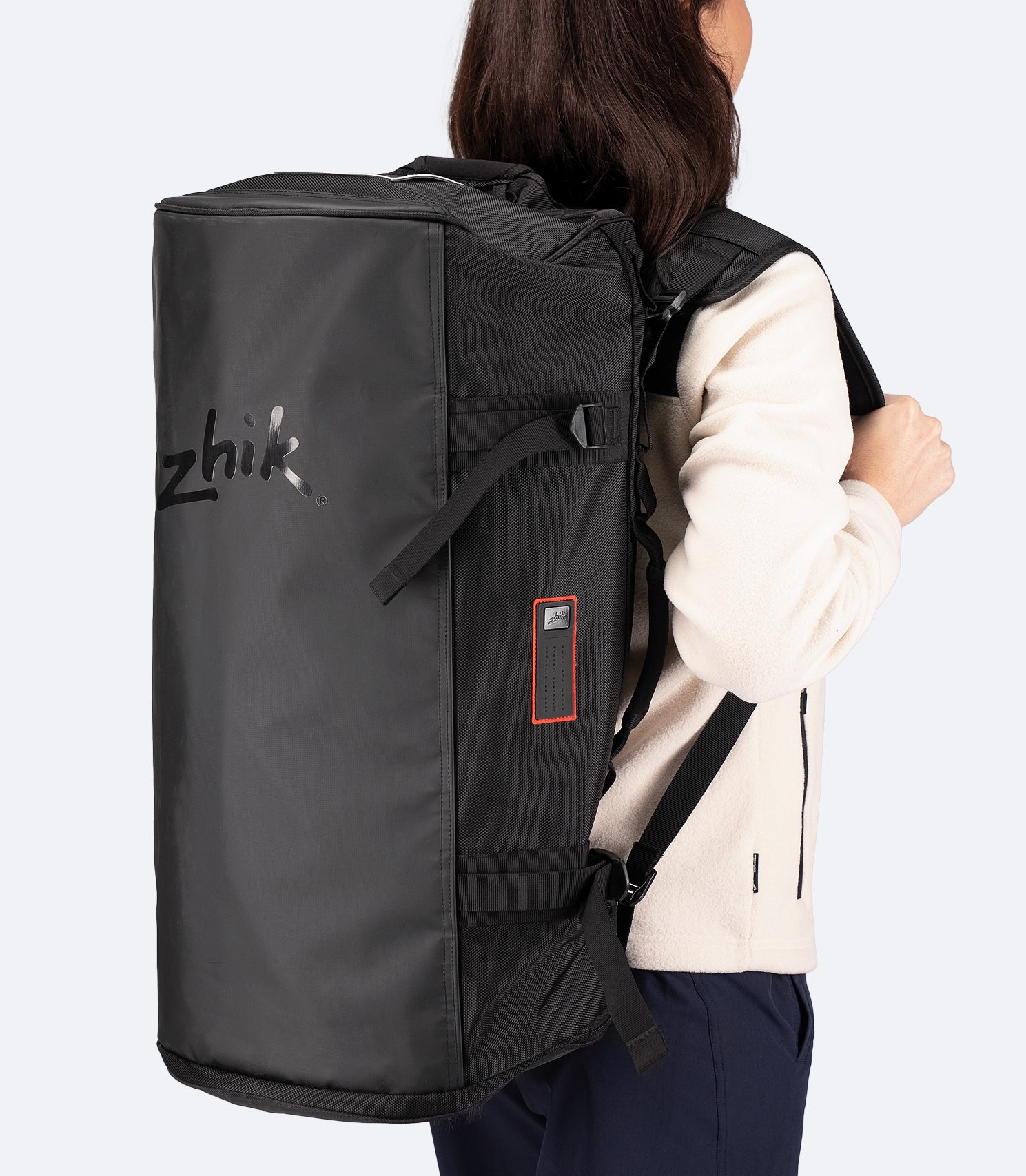 Rear view of model wearing the Zhik 55L Duffel Bag in black as a backpack, highlighting padded shoulder straps and haul handles