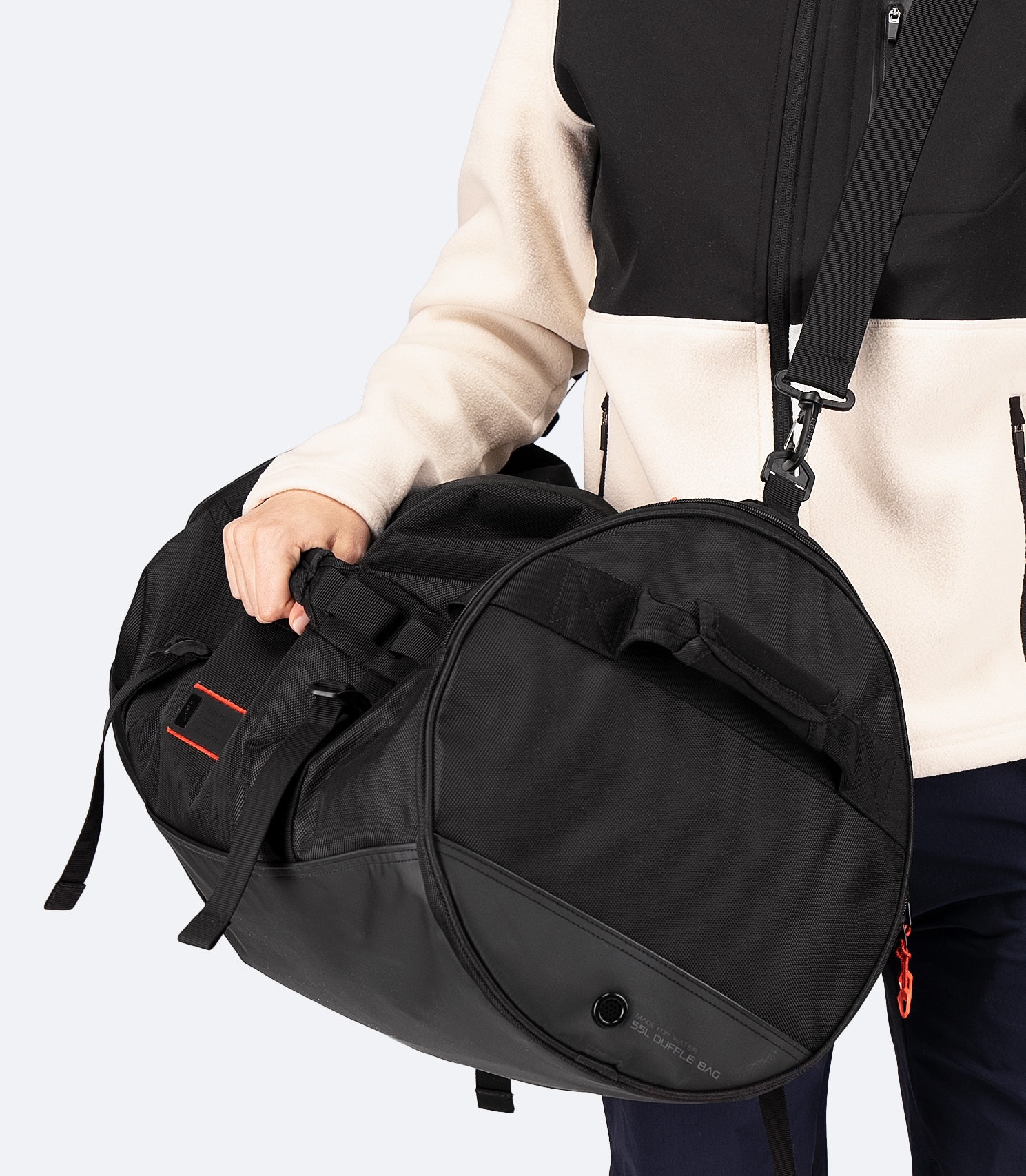 Front view of model carrying the Zhik 55L Duffel Bag in black, featuring a rugged design, reinforced haul handles, and external webbing loops