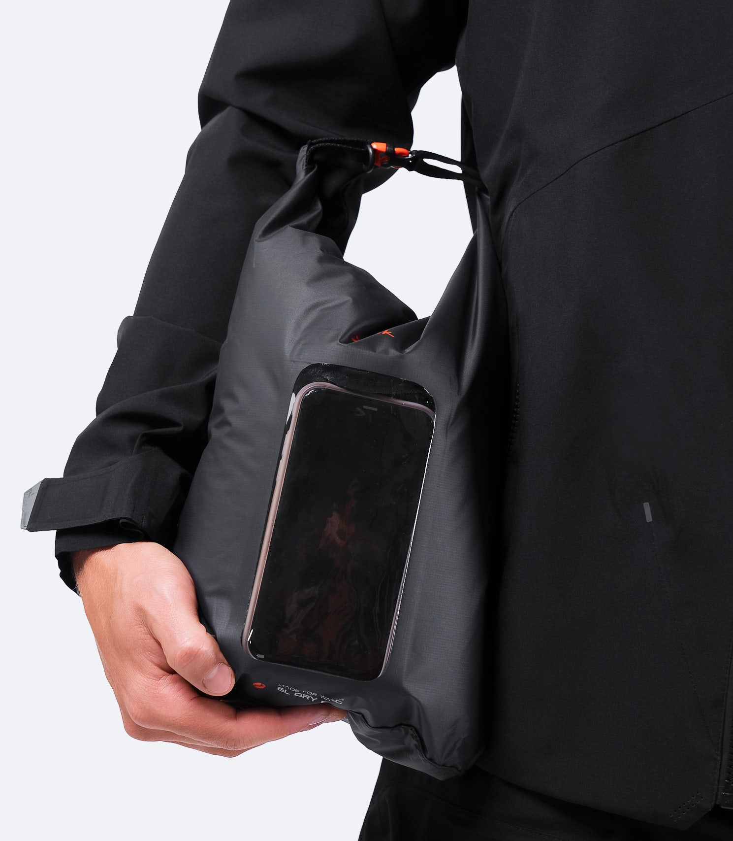 Zhik 6L Roll Top Dry Bag in black, held under arm with a phone inside its touch-sensitive screen pocket.
