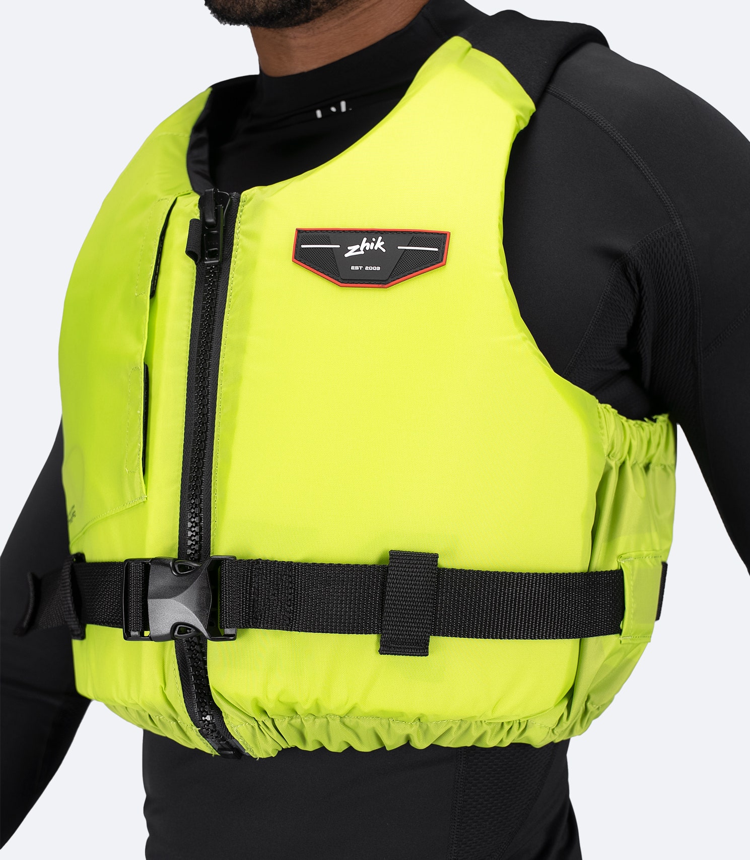 Side view of Zhik Active PFD in lime green on model, showing snug fit and adjustable waist strap with buckle.