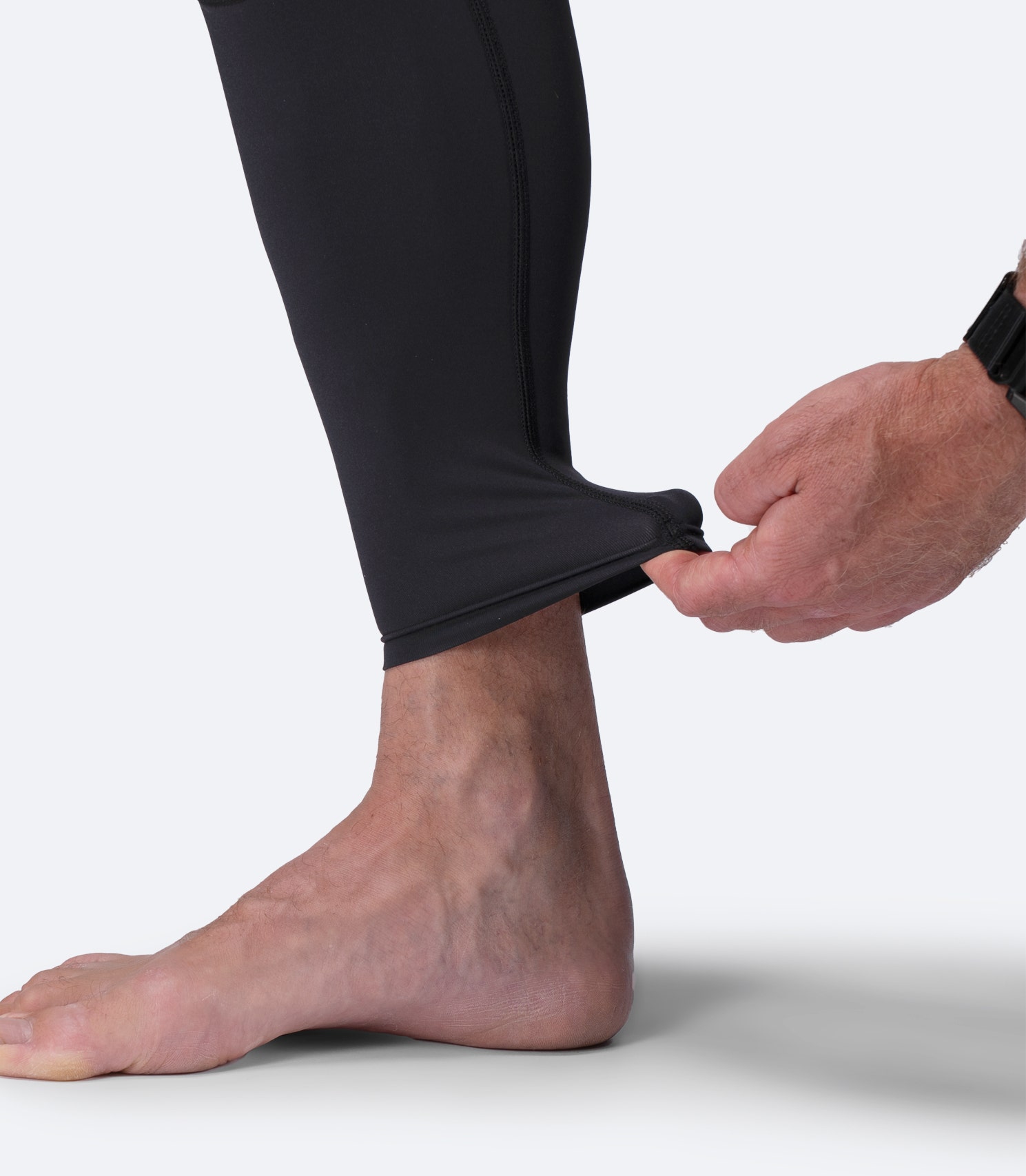 Close-up of Zhik DeckBeater X Pant in black at ankle, with hand stretching Repreve recycled fabric for flexible fit