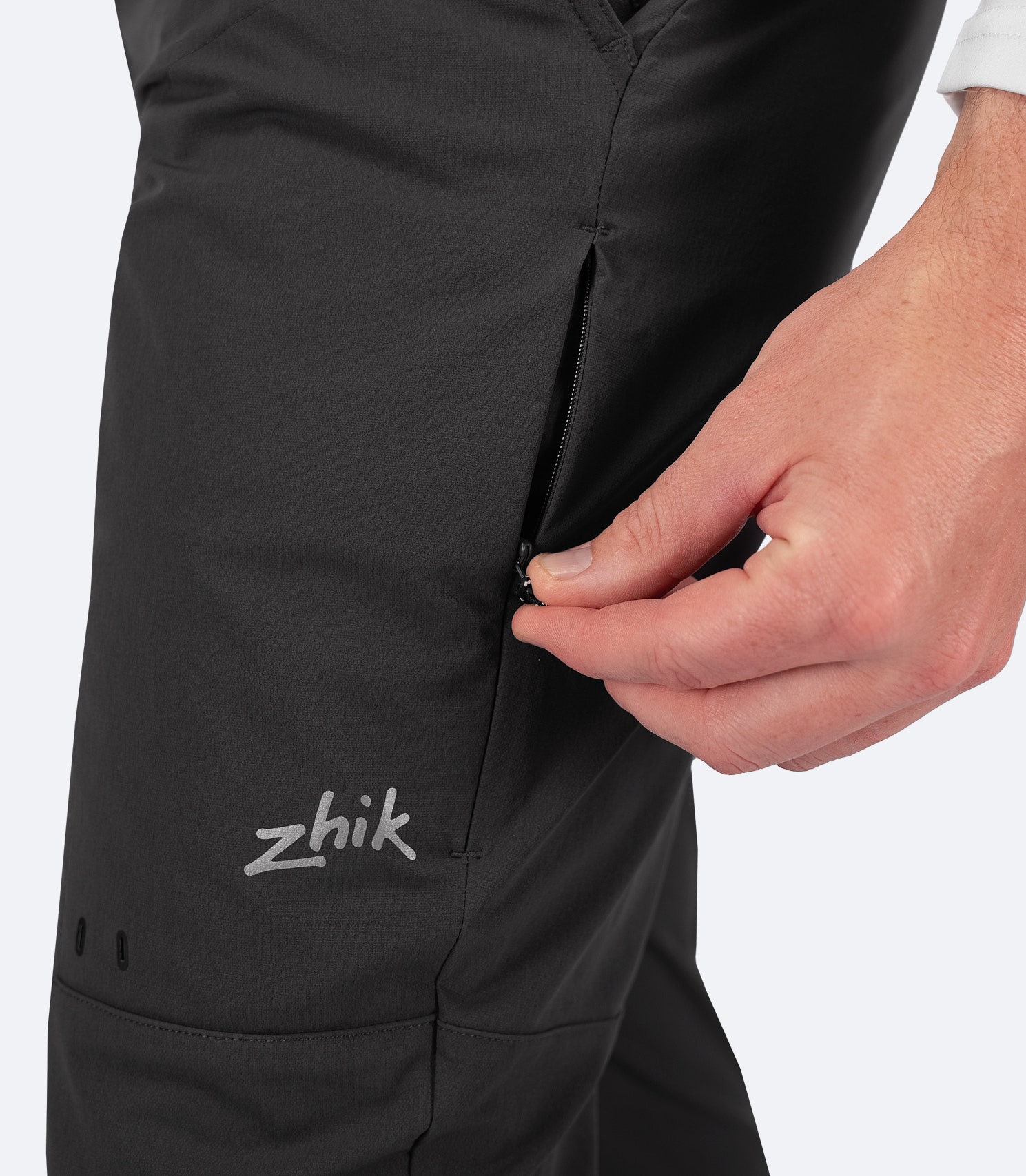 Close-up side profile of Zhik Men's Dark Grey Deck Pant showing the zippered utility pocket and Zhik logo, designed for secure storage and durability