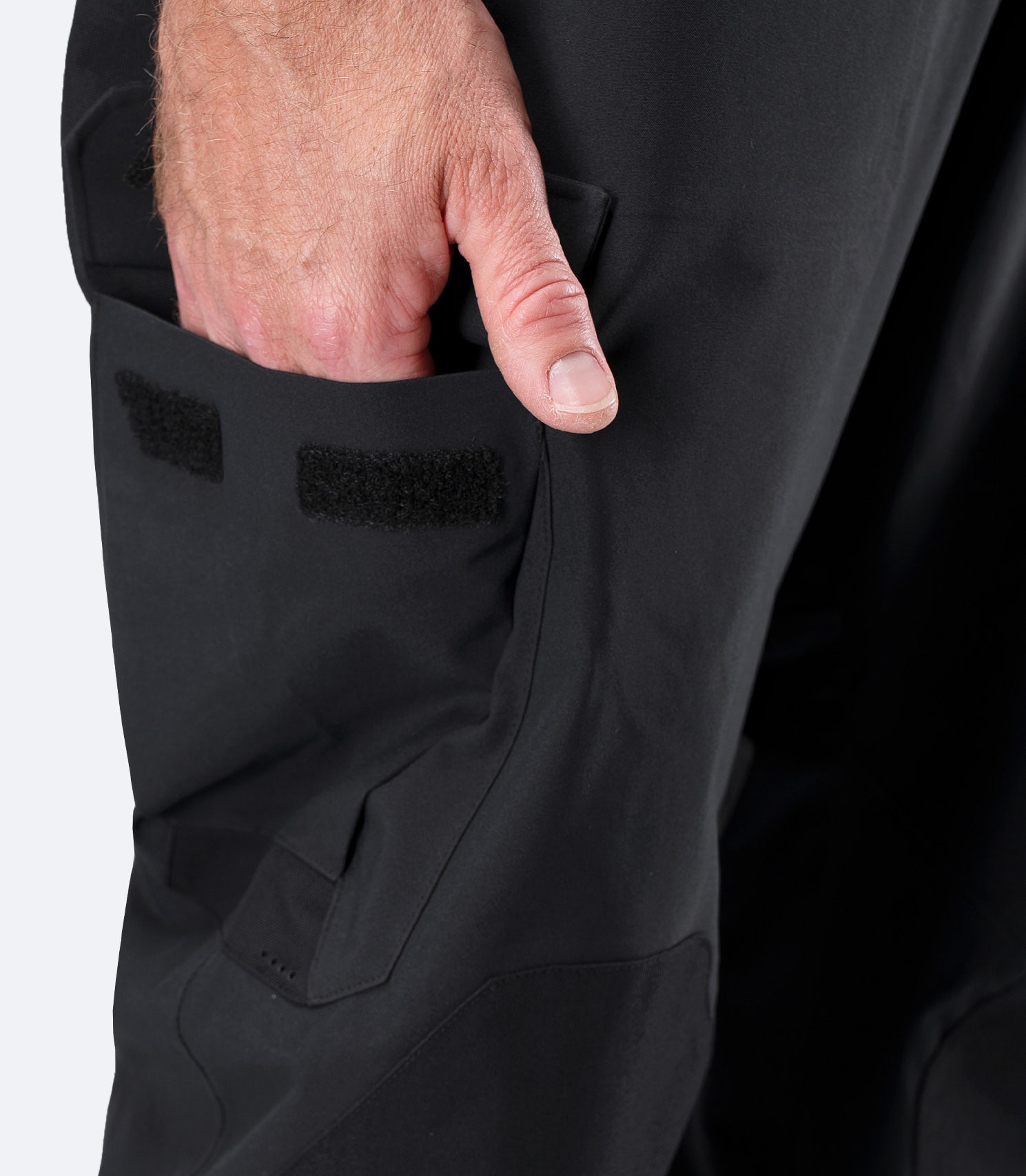 Close-up of hand in oversized side pocket near knee on Zhik Men's INS400 Performance Pant in black with water-resistant zip