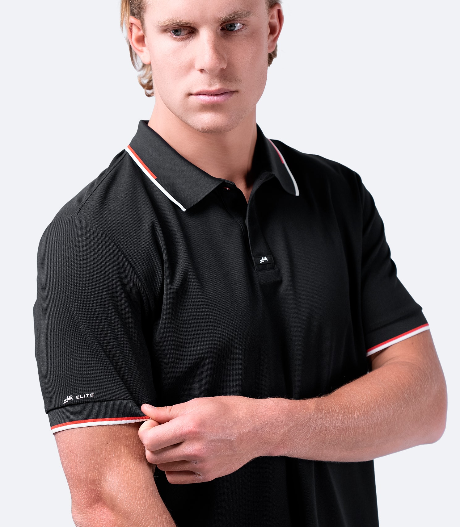 Close-up of Zhik Men's Elite Polo in black, showing textured pique fabric, structured collar, and contrast stripe detailing.