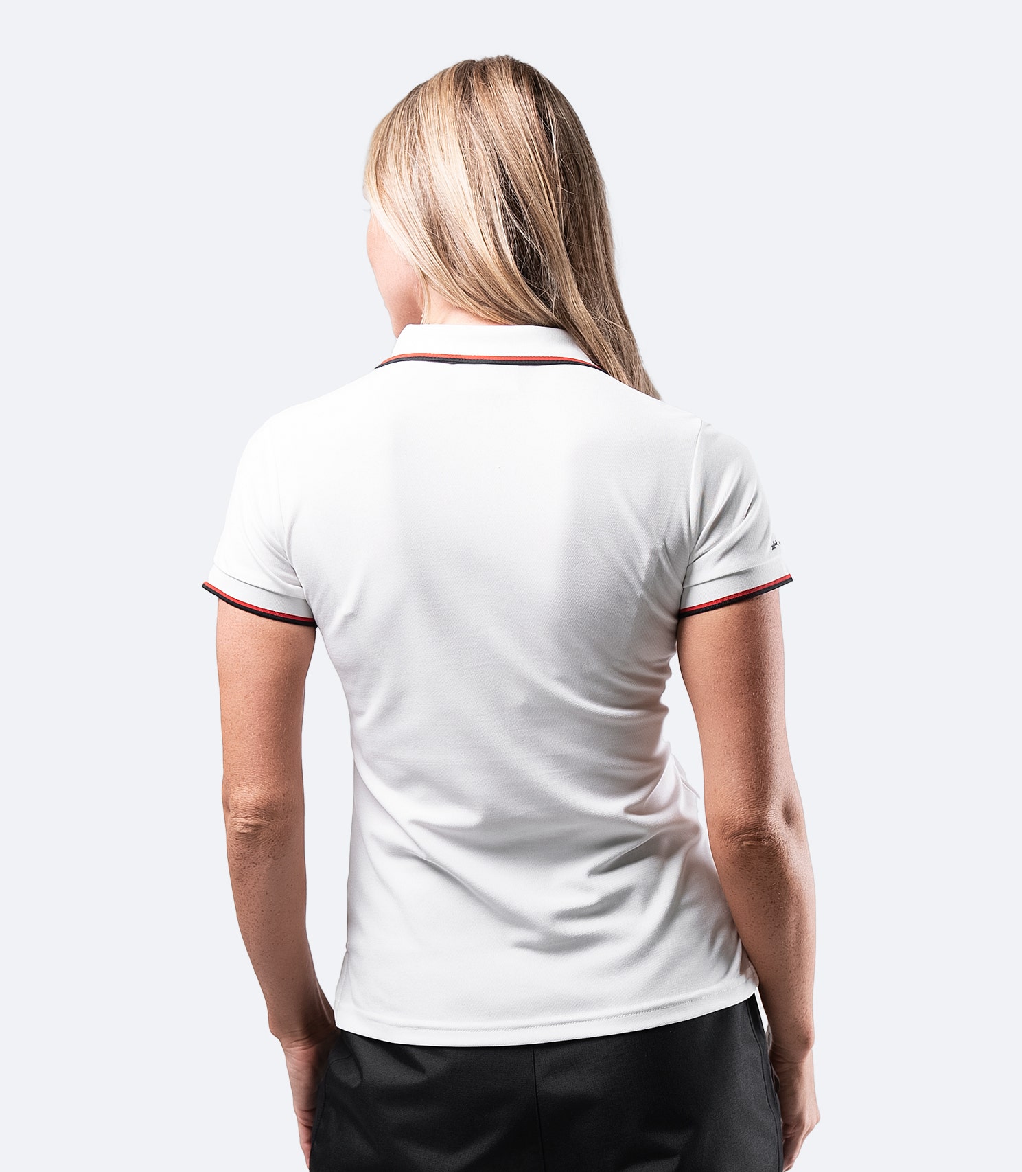Back view of Women's Elite Polo in White with breathable pique fabric and moisture-wicking properties.