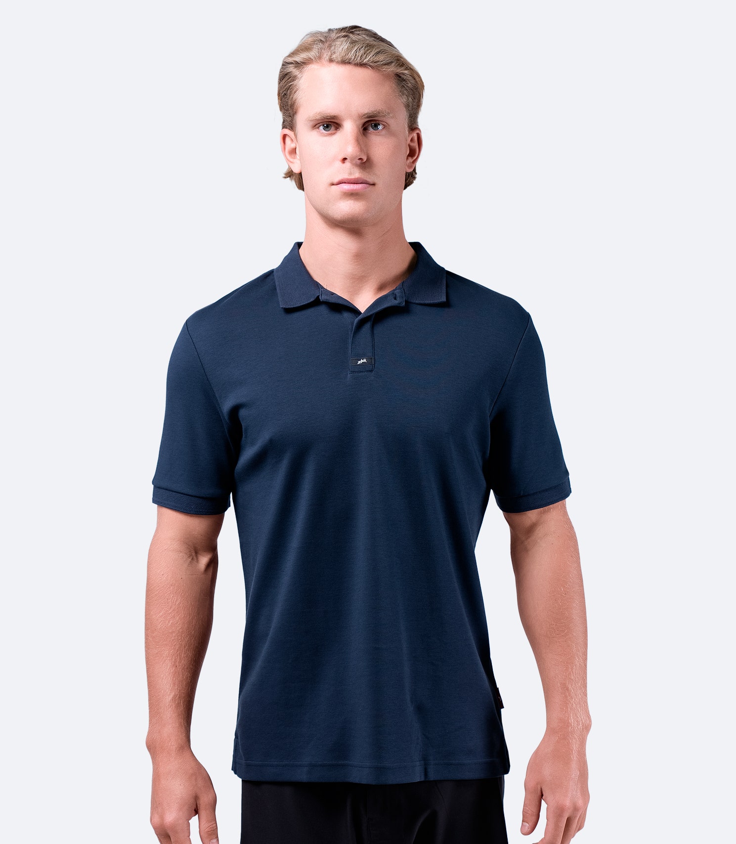 Model wearing Zhik Men's Pima Cotton Polo in navy, featuring a comfortable fit with a hidden center button.