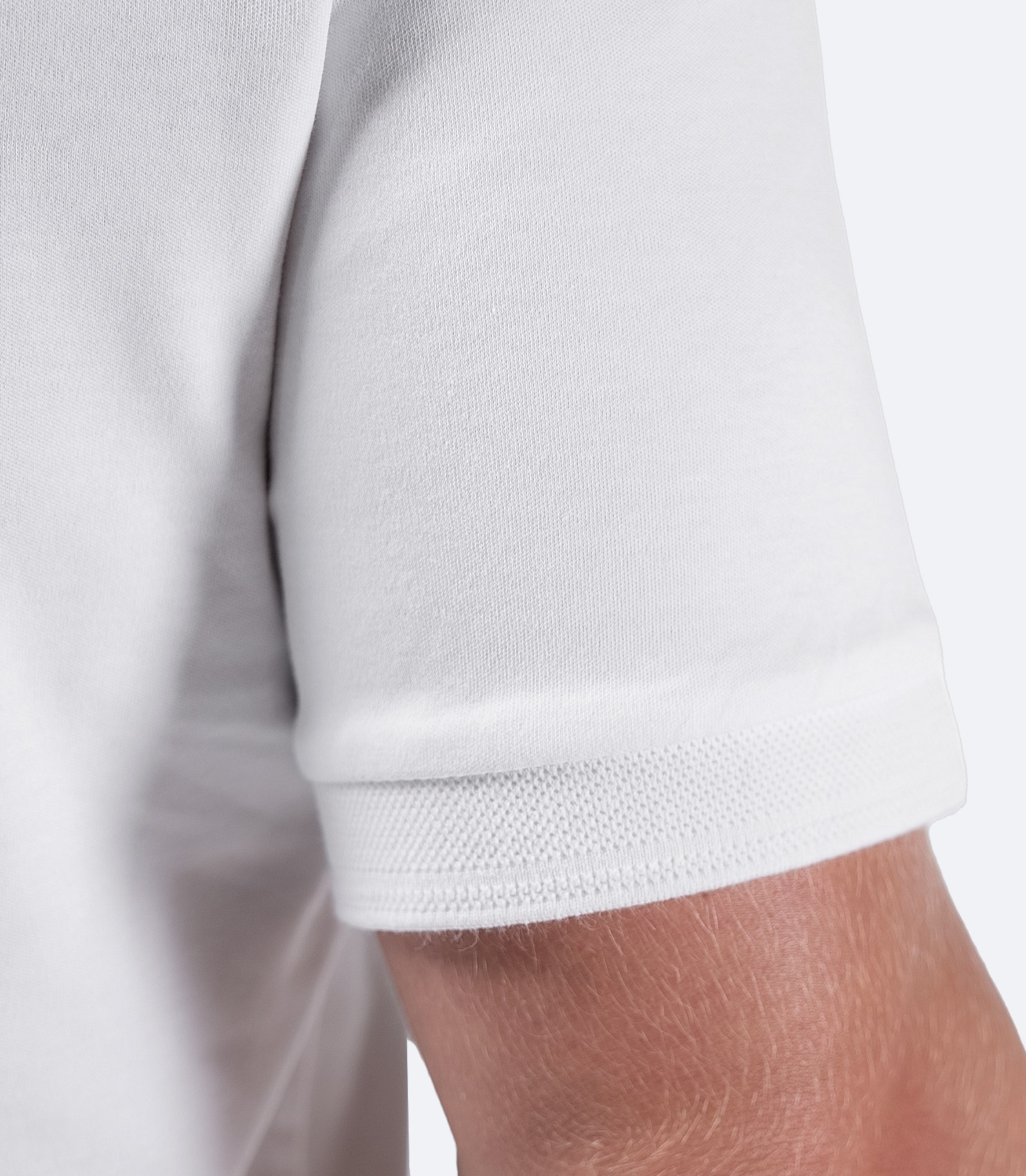 Close-up of Zhik Men's Pima Cotton Polo sleeve in white, showcasing premium cotton fabric and fine stitching.