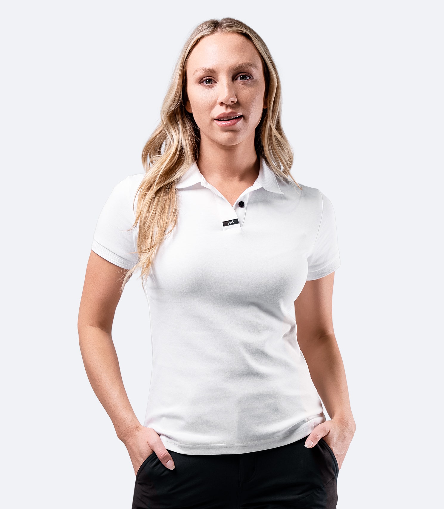 Model wearing Zhik Women's Pima Cotton Polo in white, made from soft, breathable Supima cotton with a stylish hidden button.