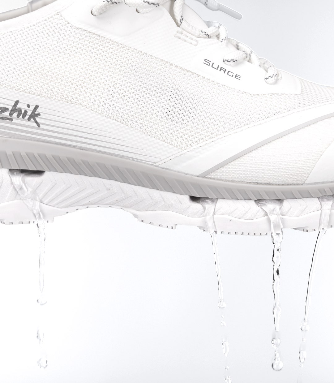 Zhik Surge Shoe in white with water flowing from the sole, highlighting the integrated side-ejection drainage system.