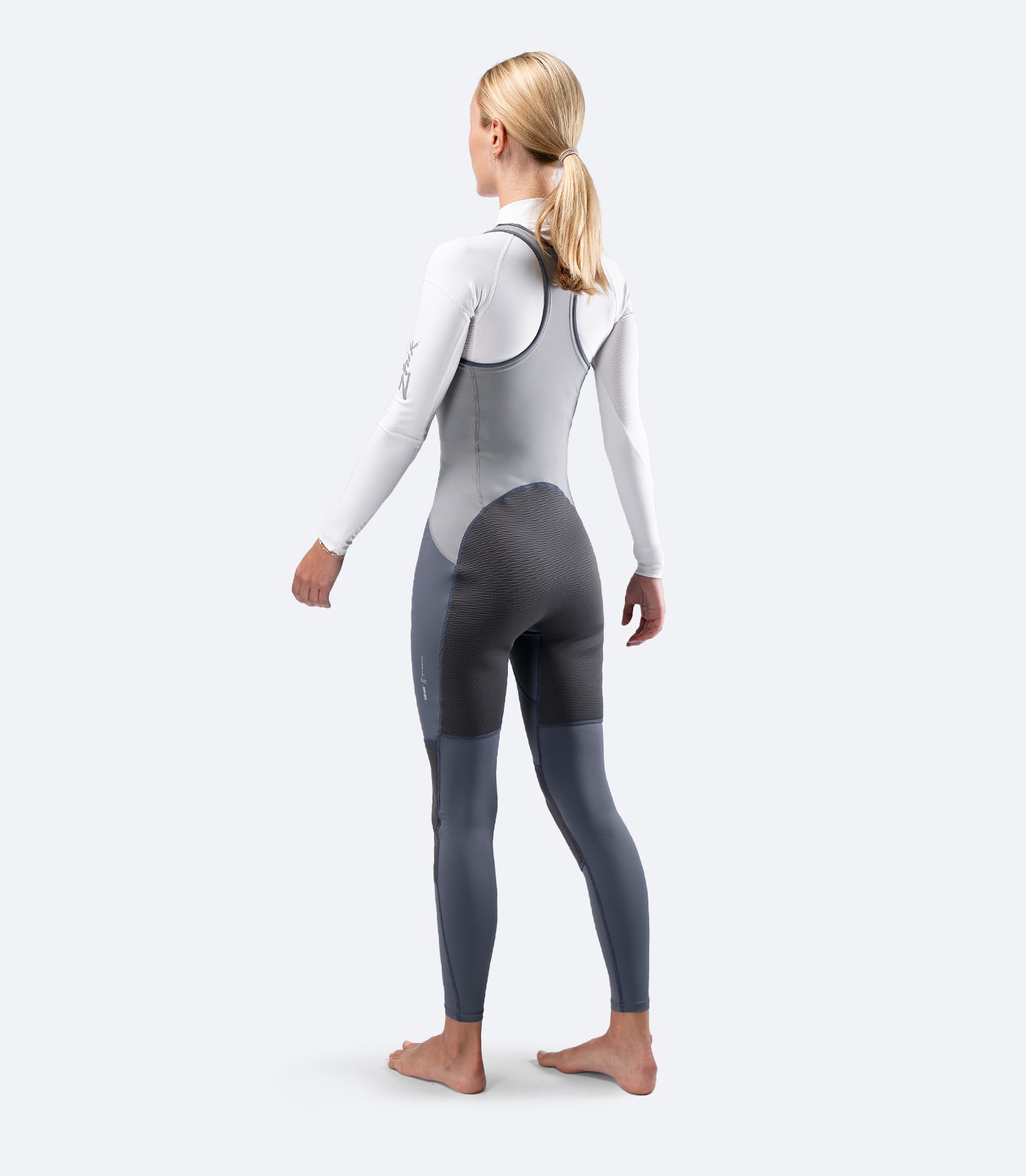 Rear diagonal view of Zhik Women's Hybrid Gear Performance Skiff Suit in grey, highlighting seat reinforcement and racerback design