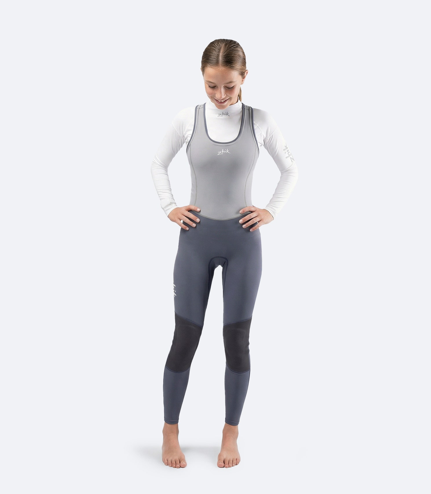 Front view of Zhik Youth Hybrid Gear Performance Skiff Suit in Grey on female model, 3D body-mapped fit for movement