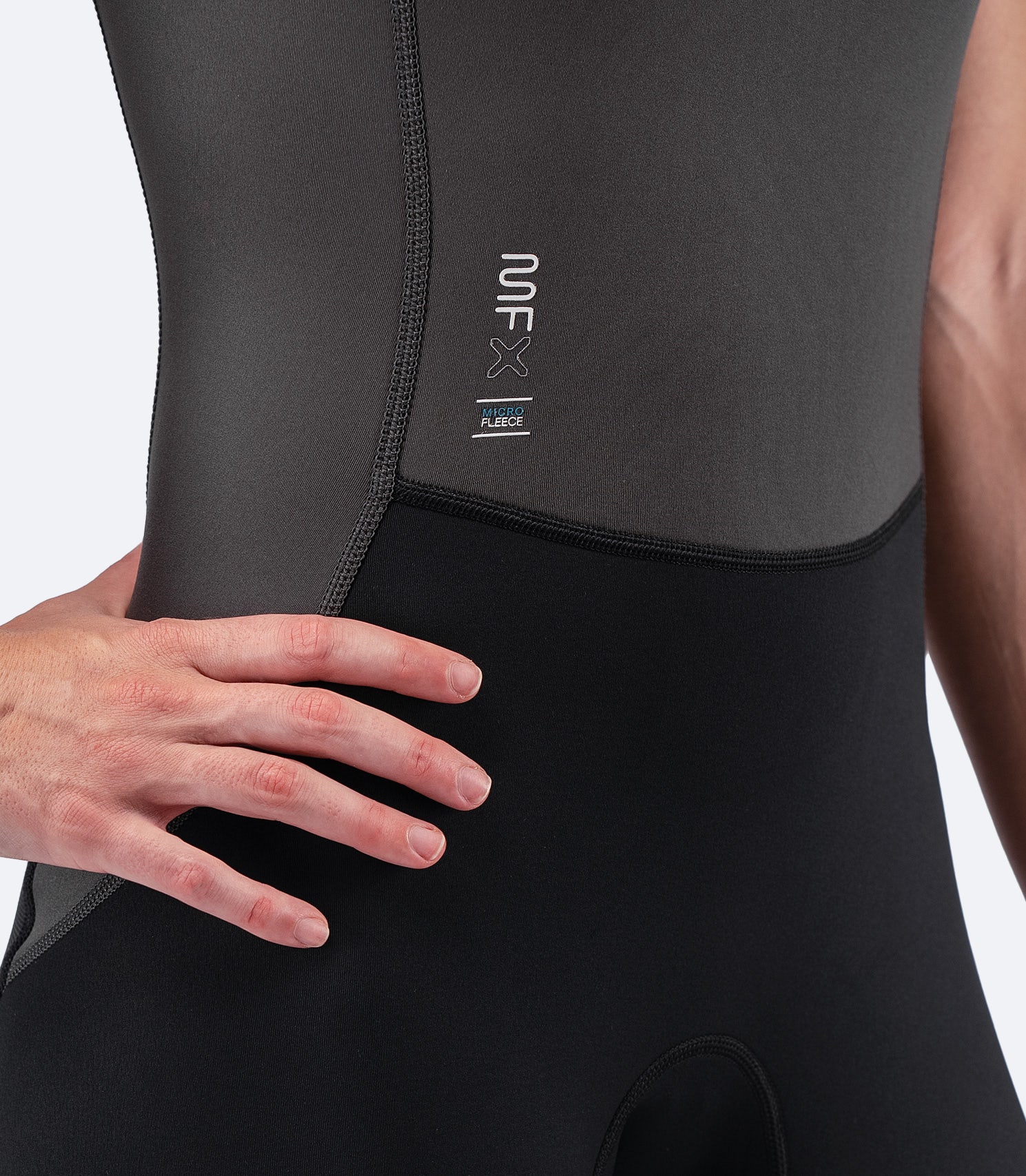 Close-up of Zhik Women's MicrofleeceX Skiff Suit logo and flatlock seams, designed for durability and comfort with eco-friendly construction.