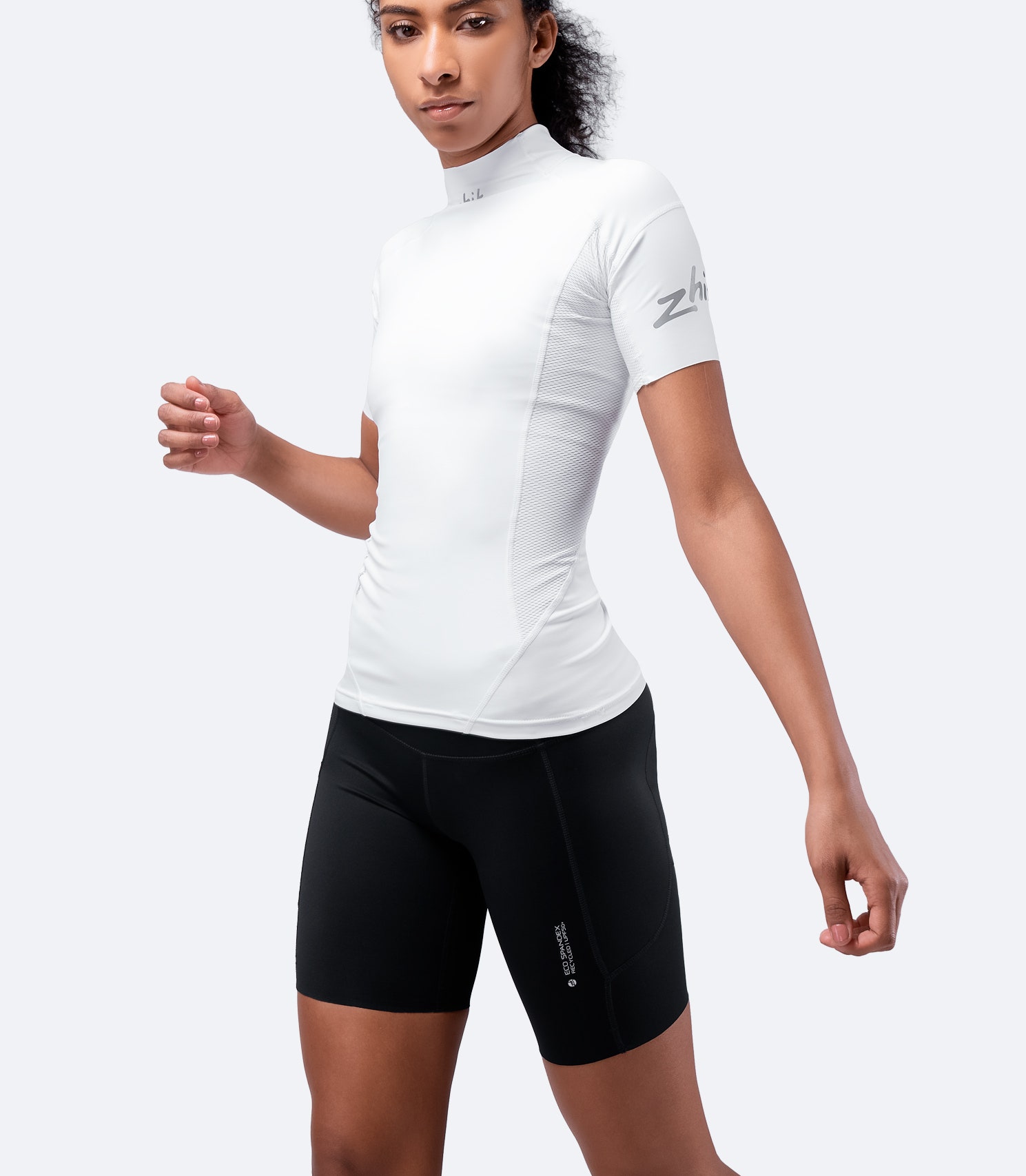 Front view of Zhik Women's Eco Spandex Shorts in black, paired with a white Eco Short Sleeve Top, showcasing a performance fit and UPF 50+ protection.