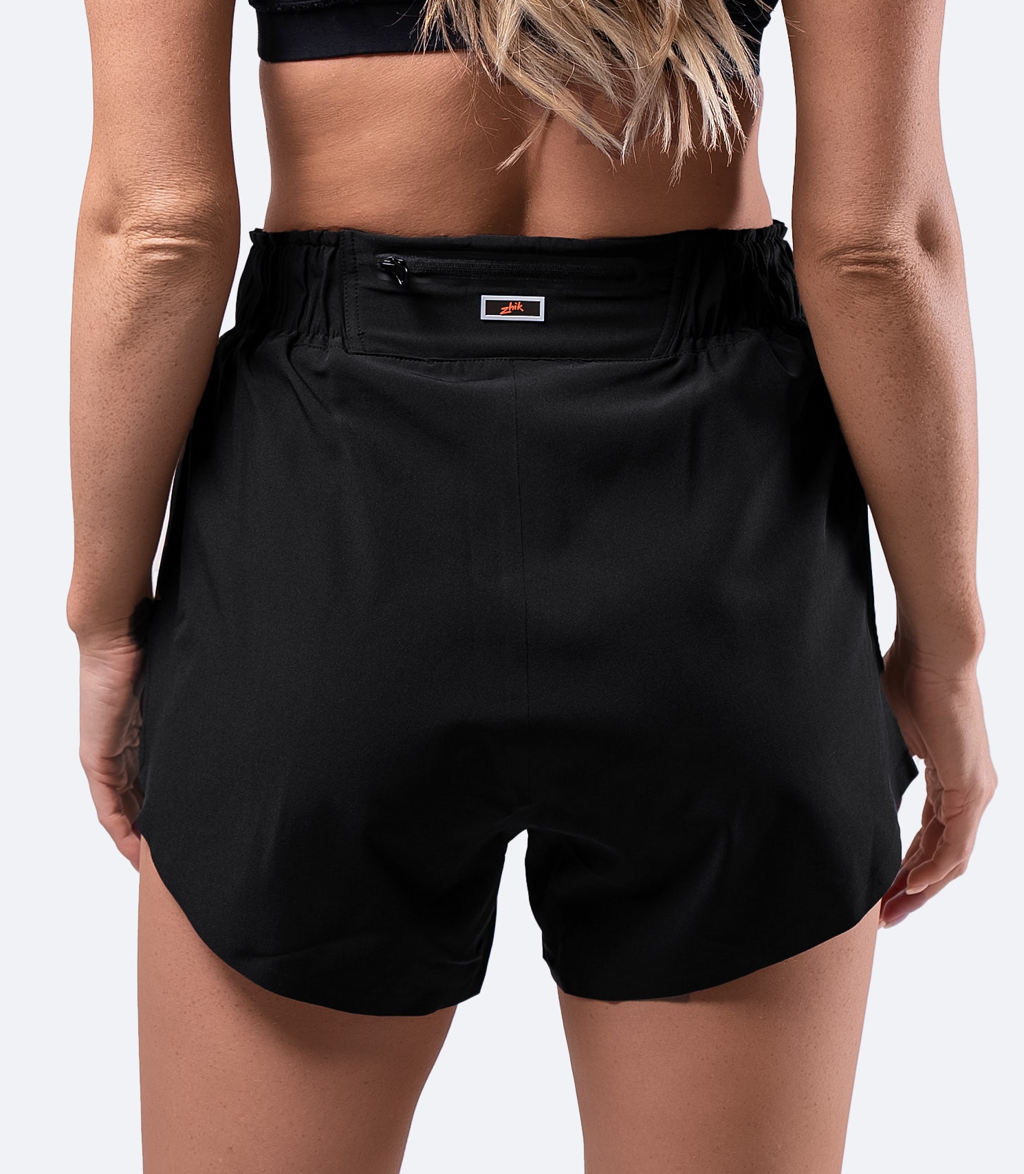 Back view of women's black board short – high-waisted with a zippered rear pocket and reinforced seams for durability.