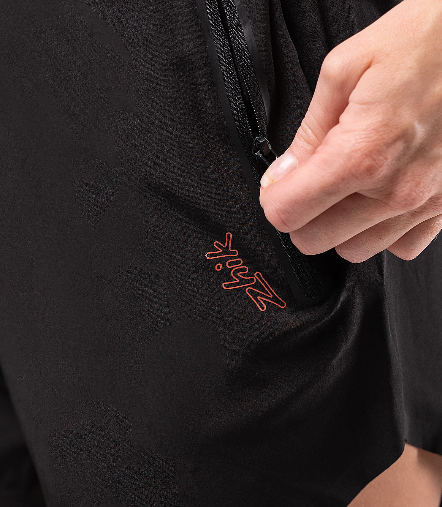 Side zippered pocket detail on women's black board short – secure storage with a sleek, reinforced design.