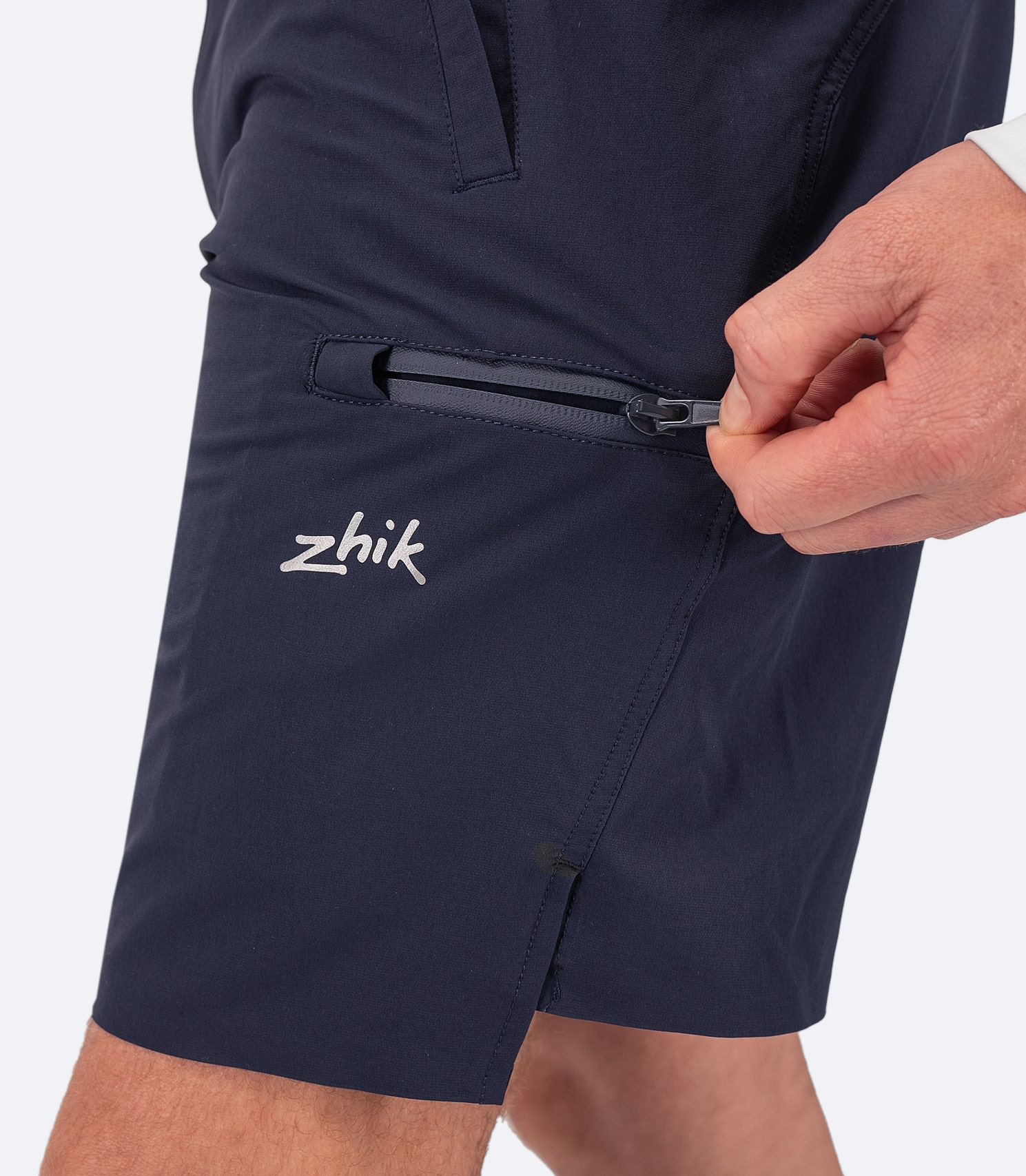 Perfil lateral de los pantalones cortos de cubierta Navy para hombre de Zhik, que destaca el bolsillo en el muslo con cremallera resistente al agua y los bolsillos laterales para un almacenamiento seguro.