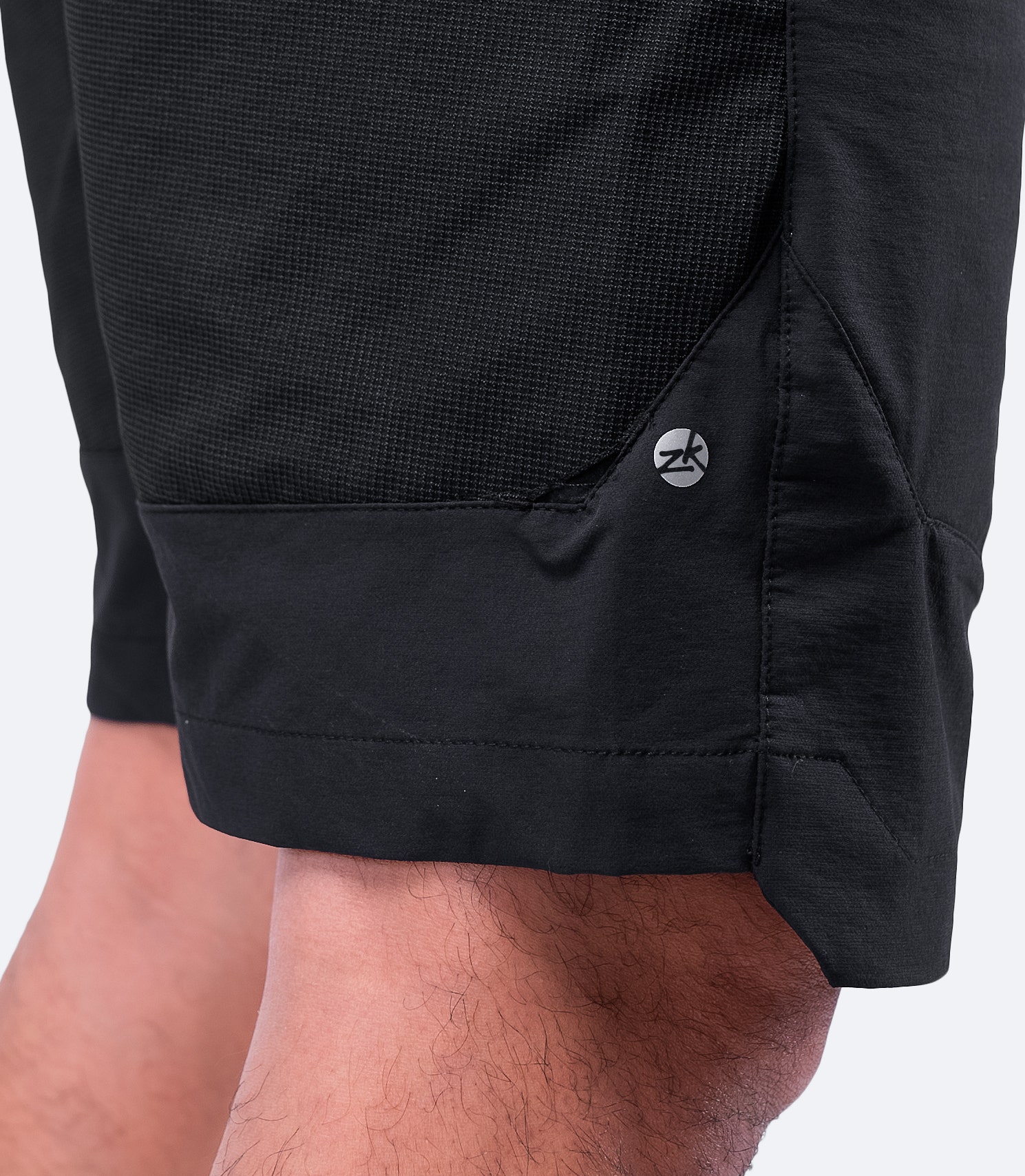 Vista detallada de las costuras reforzadas y el tejido impermeable duradero y elástico en 4 direcciones de los pantalones cortos Elite negros para hombre de Zhik.