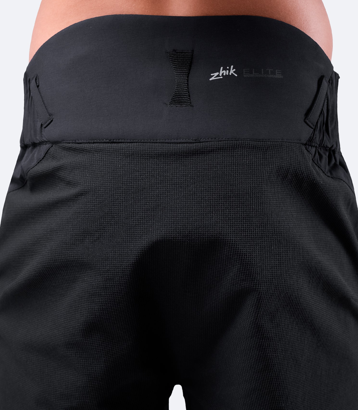 Vista trasera de cerca de los pantalones cortos Elite negros para hombre de Zhik, con un panel trasero alto para proteger la zona lumbar y un lazo de secado característico.