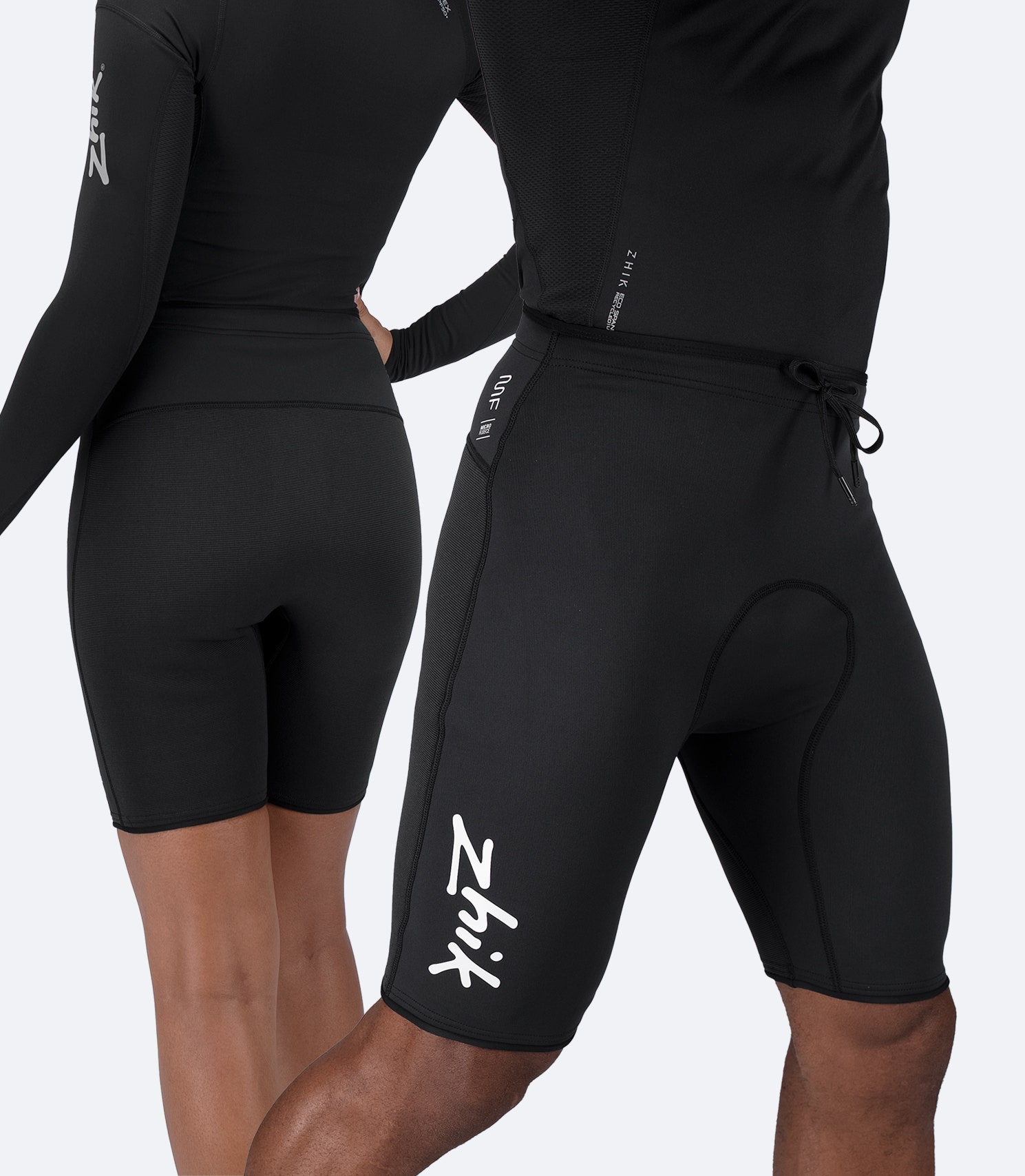 Side view of Zhik Microfleece™ Performance Shorts in black worn by male and female athletes, showing high-stretch fit.