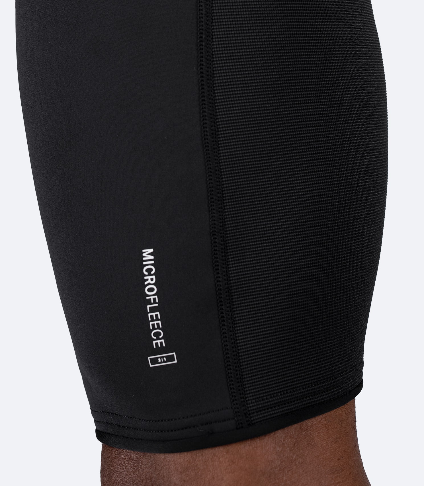 Close-up of black Zhik Microfleece™ Shorts fabric on male, showing 4-way stretch neoprene and flatlock seam construction.