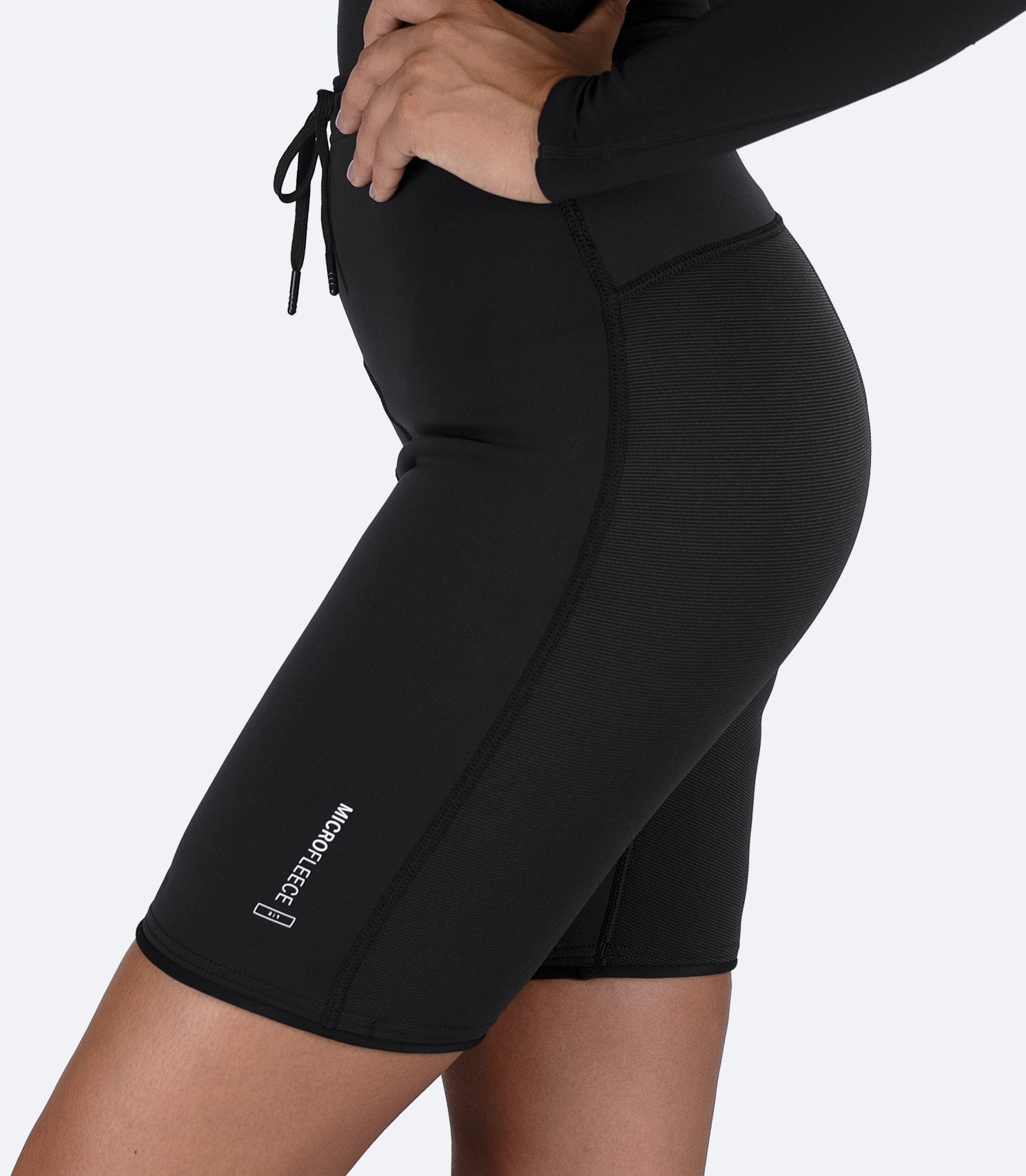 Side view of black Zhik Microfleece™ Performance Shorts on female model, showing curved fit and smooth seam lines.