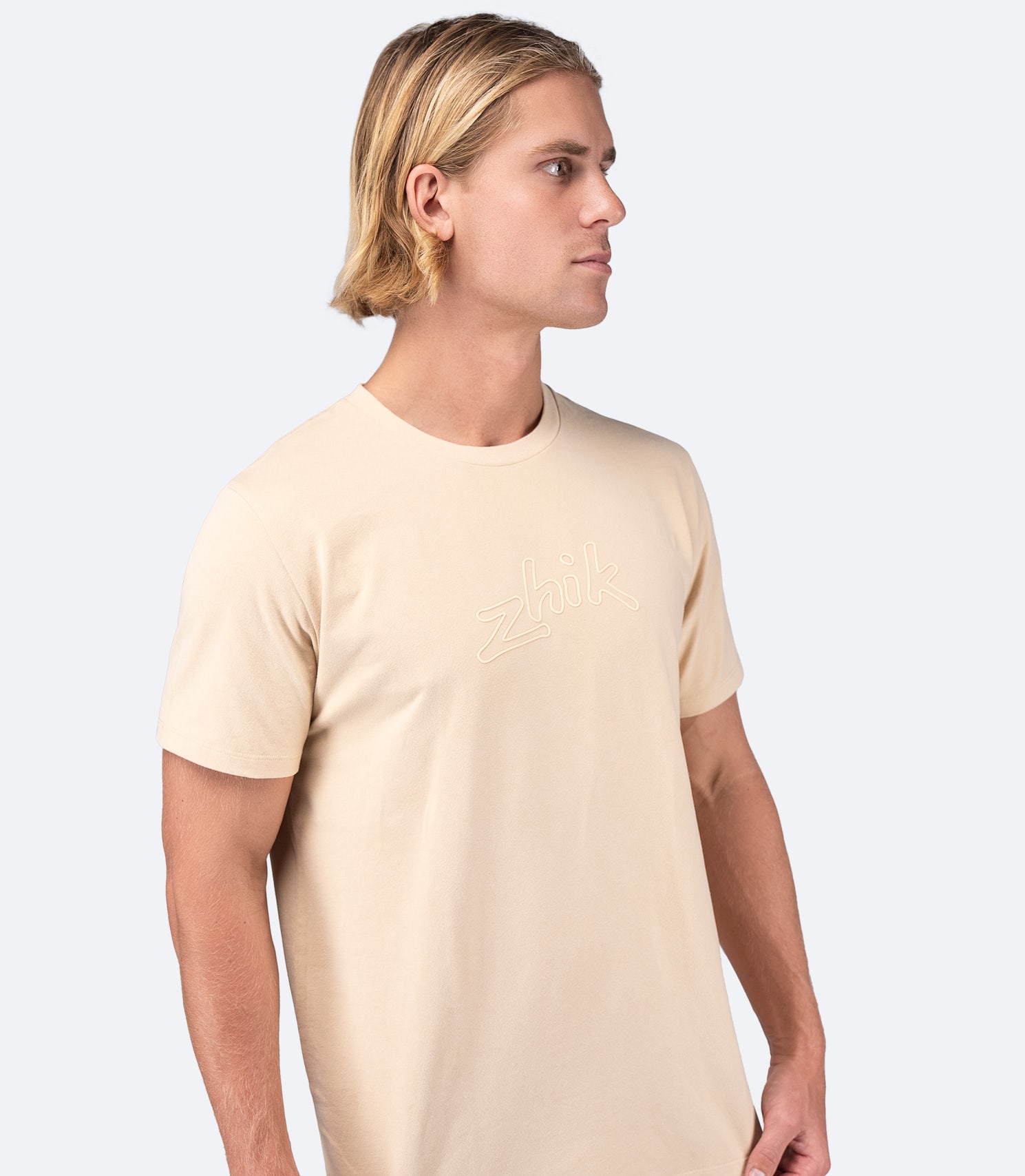 Model wearing Zhik Men's Logo Cotton T-Shirt in Sand, designed for on and off the water with a casual, relaxed fit.