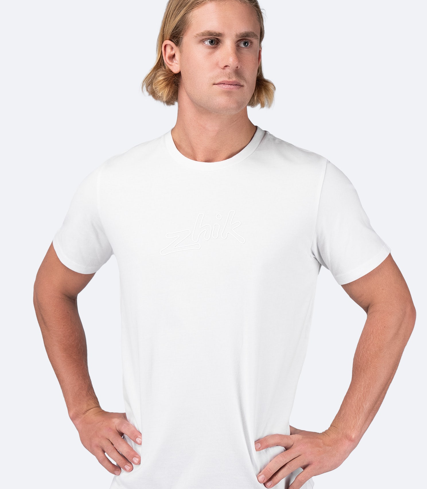 Model wearing Zhik Men's Logo Cotton T-Shirt in white, designed for on and off the water with a casual, relaxed fit.