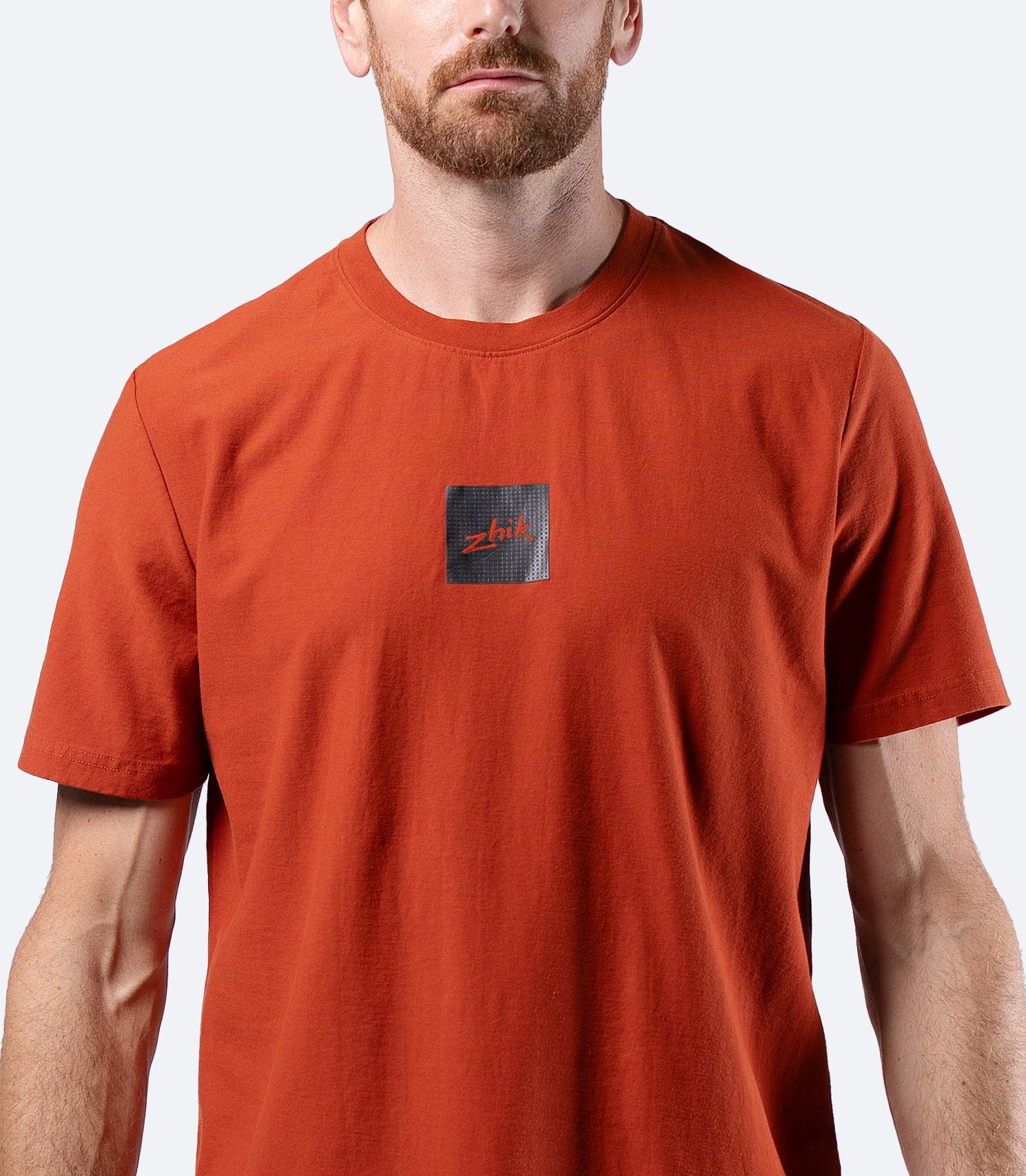 Close-up of Zhik logo on chest of Men's Carbon T-shirt in Red Earth, showing soft premium cotton fabric