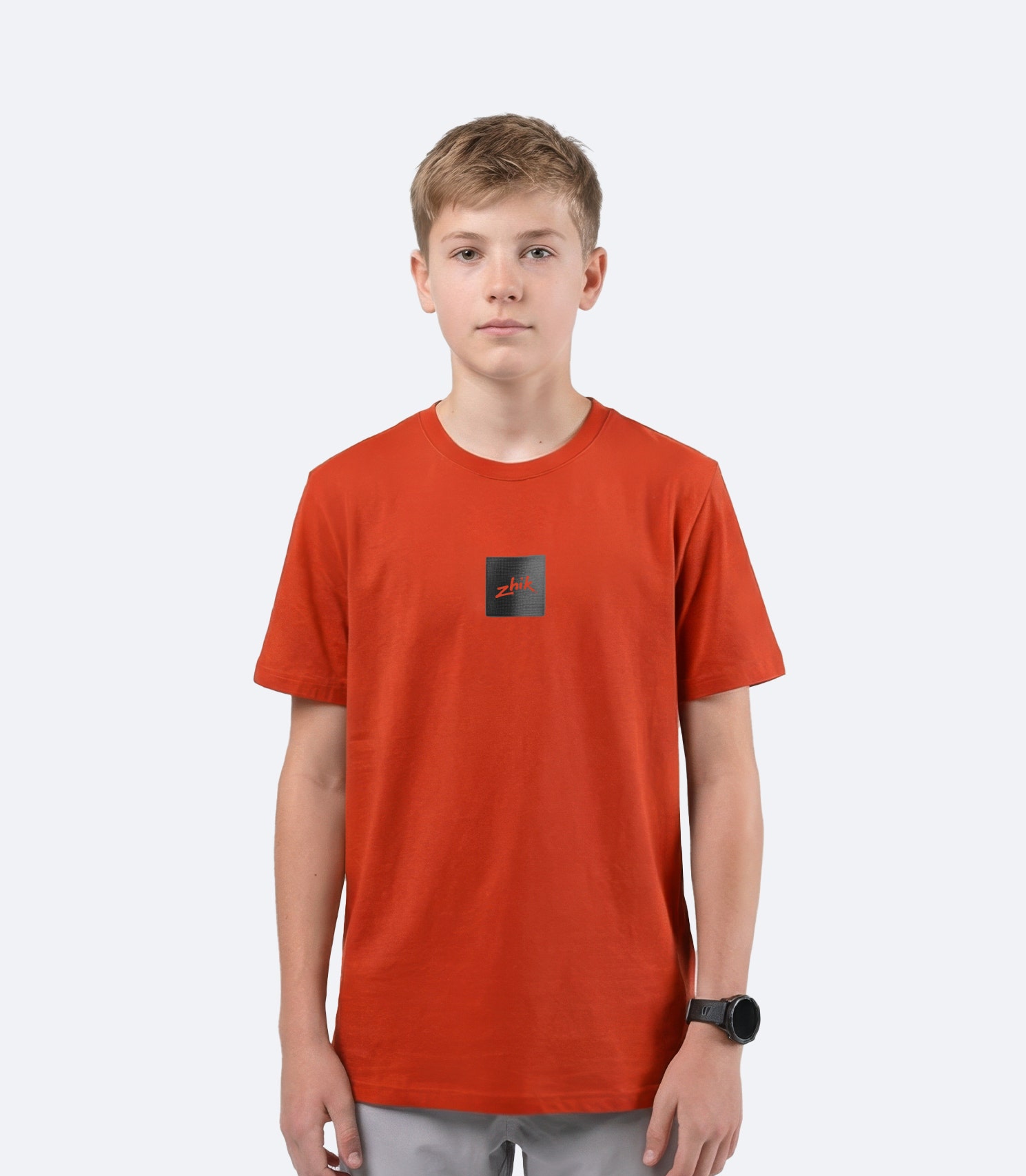 Zhik youth Carbon T Shirt in Red Earth on male model front view, showing subtle textured Carbon logo branding on chest