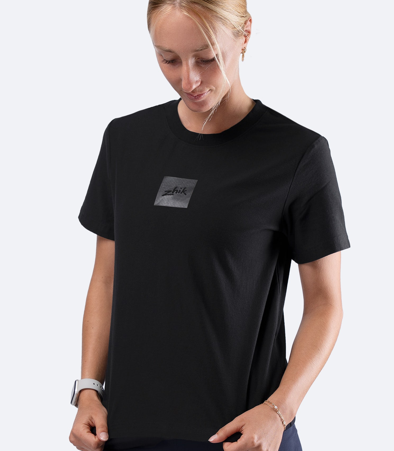 Zhik Womens Carbon T-Shirt in Black, front view with hand on waistline feeling soft 200gsm cotton fabric