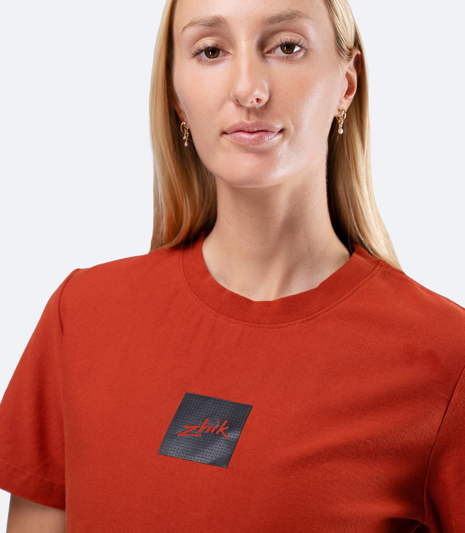 Zhik Womens Carbon T-Shirt in Red Earth, close-up of upper chest showing subtle textured Carbon logo