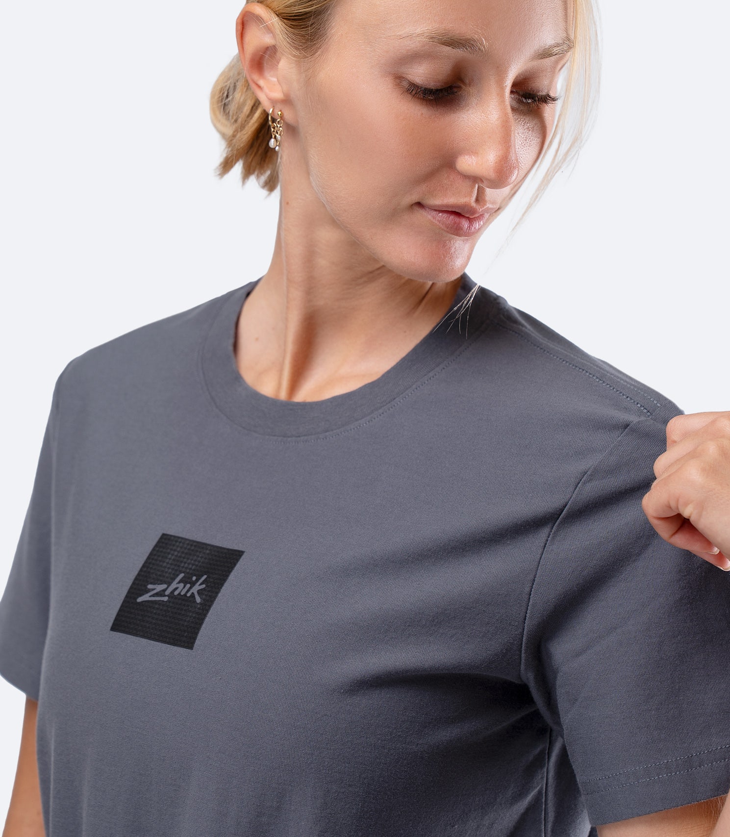Zhik Womens Carbon T-Shirt in Slate, close-up of hand on shoulder stretching durable cotton jersey