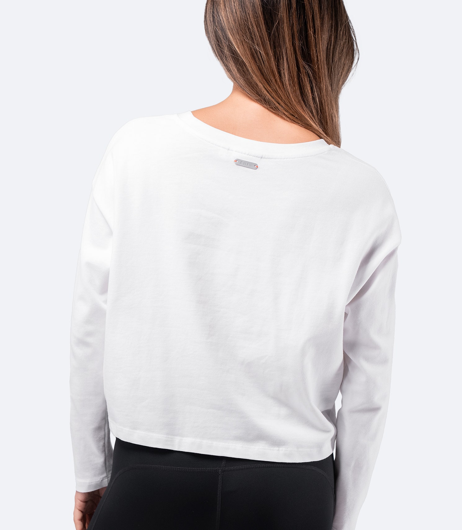 Back view of White Zhik Women's Compass Print Long Sleeve Cotton Tee – 100% cotton, super soft, and durable with a cropped cut.