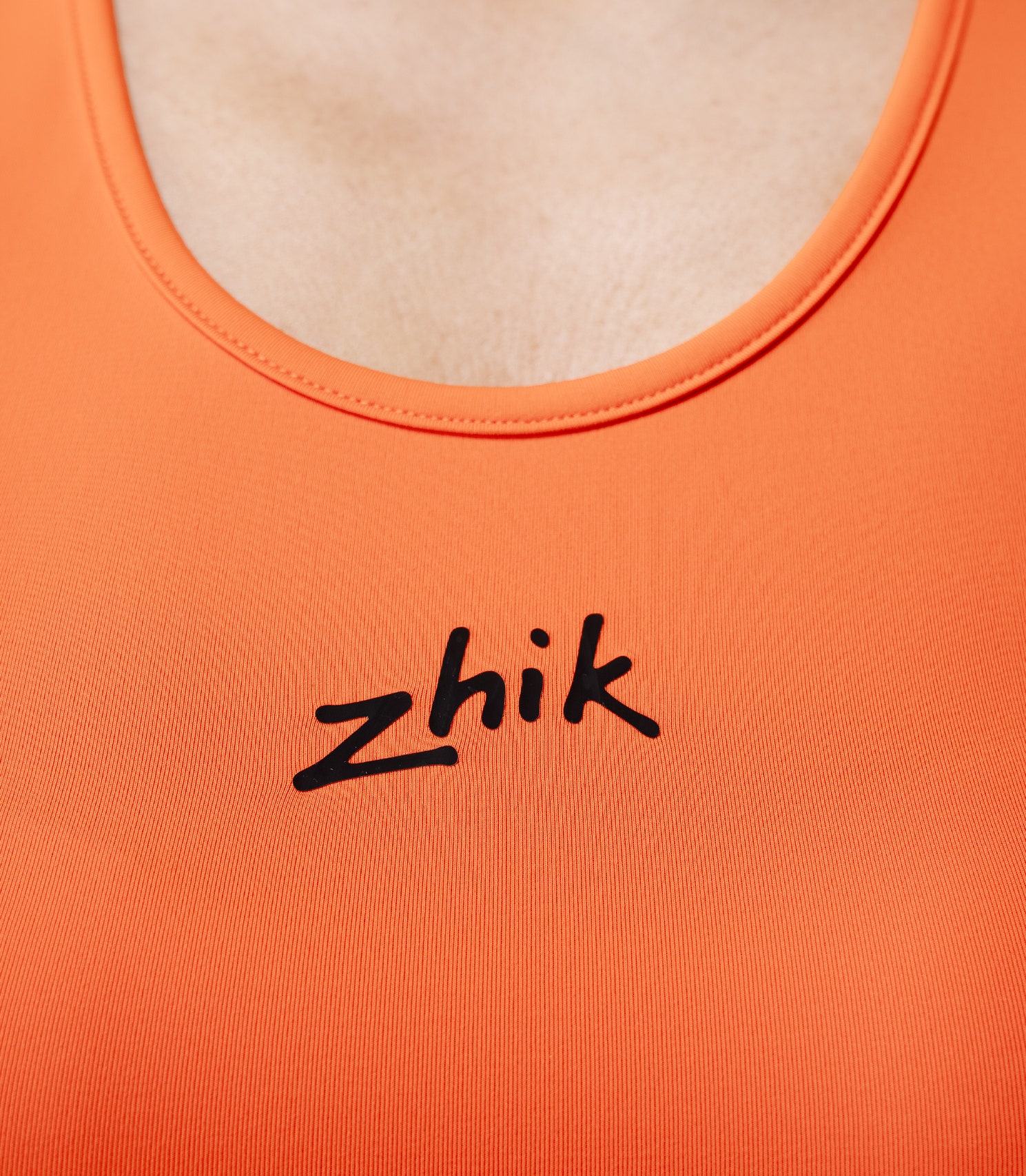Zhik Women’s Eco Spandex LT Race Singlet in flame red, close-up of chest with Zhik logo.