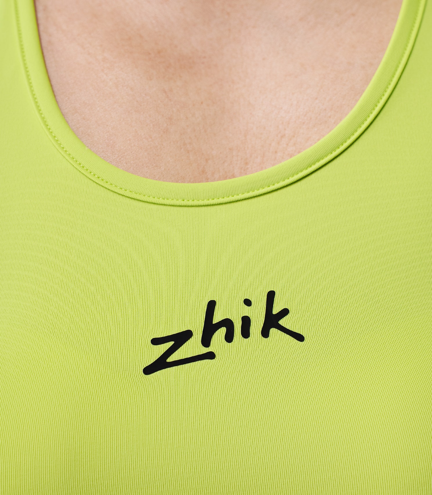Zhik Women’s Eco Spandex LT Race Singlet in lime, close-up of chest with Zhik logo branding.