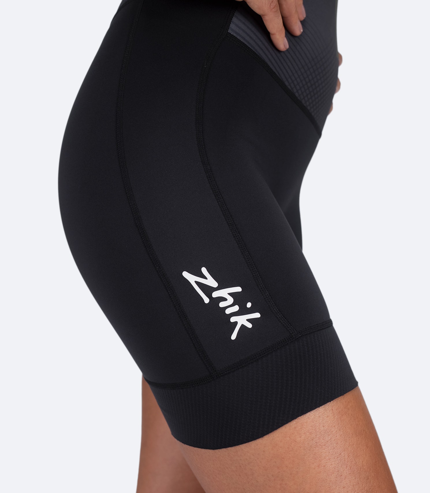 Detailed view of side knee and thigh on black Zhik Women's Performance Unisuit, featuring UPF 50+ UV protection and flatlock stitching.