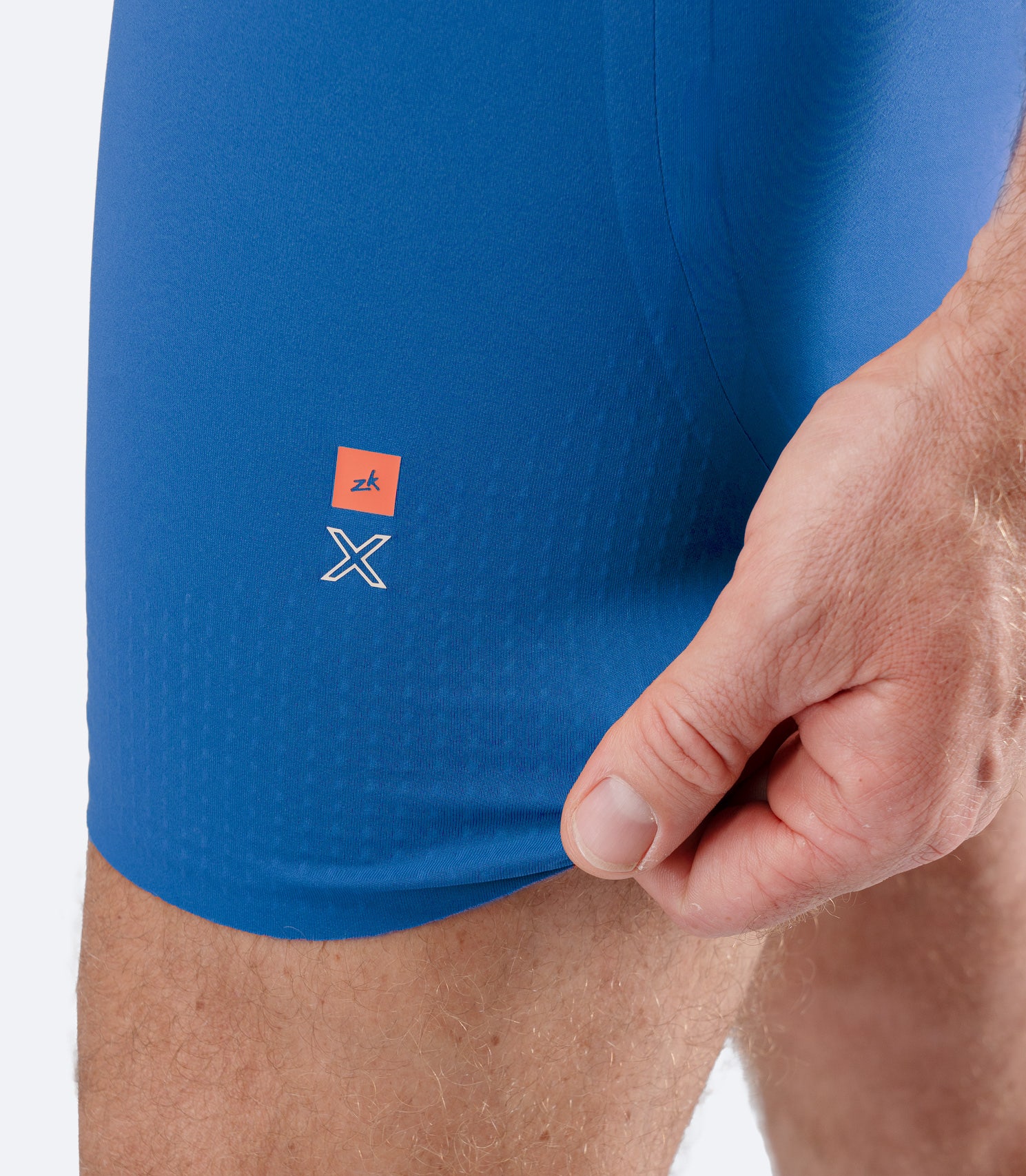 Close-up of Zhik Men’s X Unisuit in Blue with hand stretching graphene-infused leg fabric.
