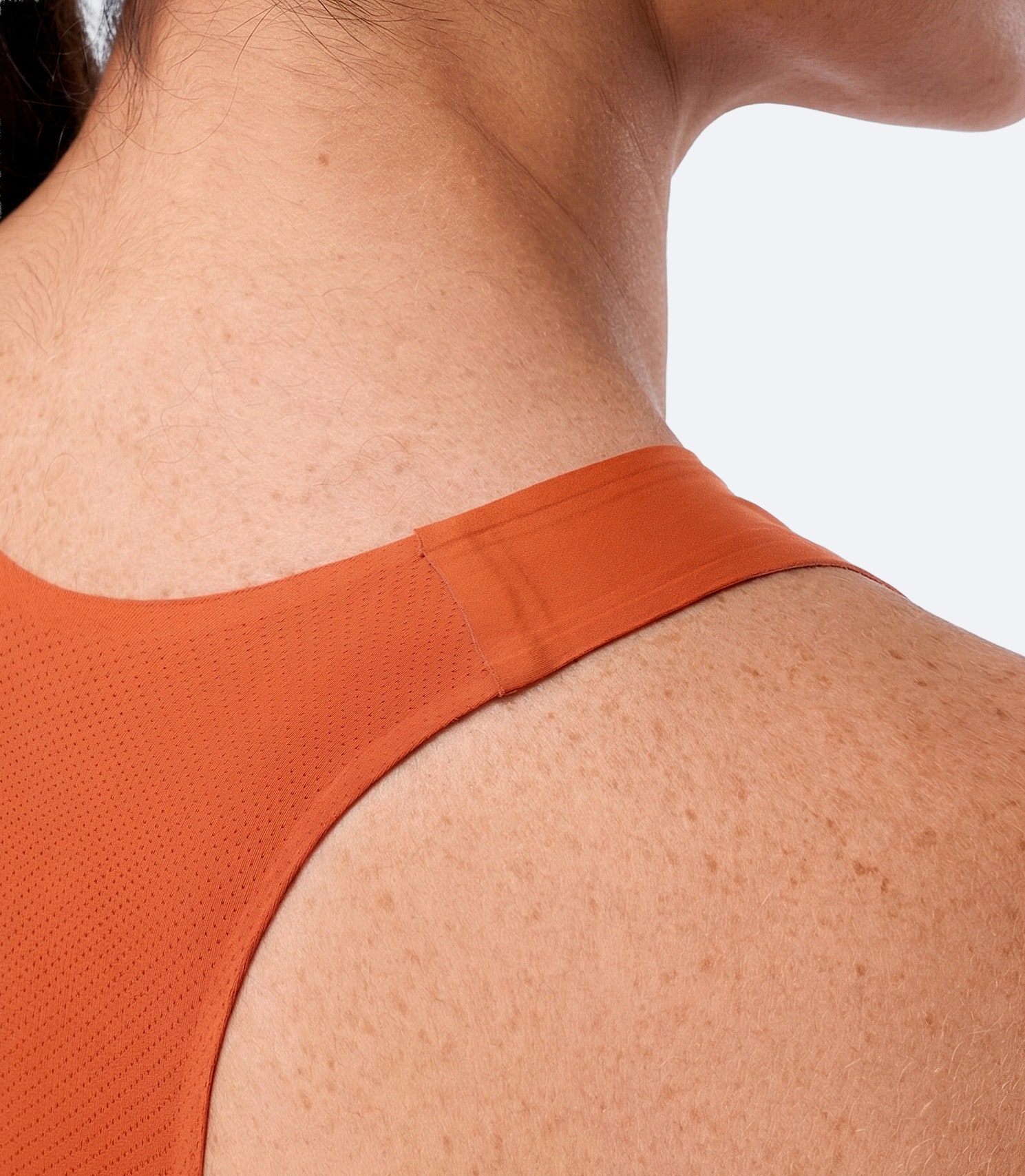 Close-up rear shoulder strap on Zhik Women's X Unisuit in Red Earth showing fused support and ergonomic design.